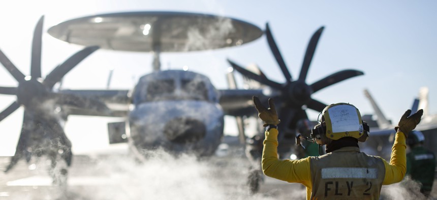 Aviation Boatswain's Mate (Handling) Airman Julian Fernando, from Yonkers, N.Y., directs an E-2D Hawkeye assigned to the "Wallbangers" of Carrier Airborne Early Warning Squadron 117 on the flight deck of the USS Abraham Lincoln.