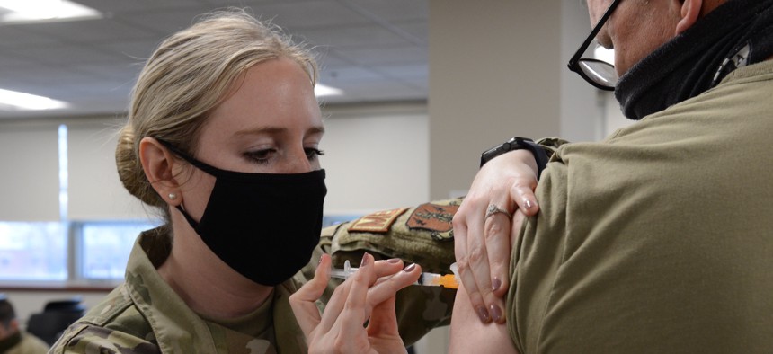 Staff Sgt. Megan Rose, (left), 155th Medical Group nurse, gives a COVID-19 vaccination dose to a Nebraska Air National Guard volunteer, Jan. 10, 2021, at the 155th Air Refueling Wing in Lincoln. 