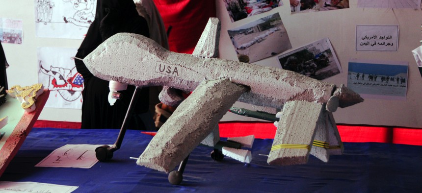 A Yemeni activist sits near models of U.S. drone and missiles displayed during a 2014 show in Sanaa, Yemen.