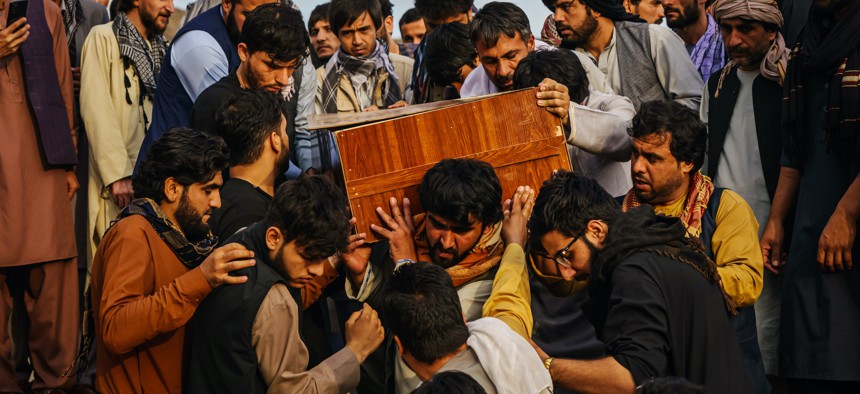 Caskets for the dead are carried towards the gravesite as relatives and friends attend a mass funeral for members of a family that were killed in a U.S. drone airstrike targeting ISIS-K militants, in Kabul, Afghanistan, Monday, Aug. 30, 2021.
