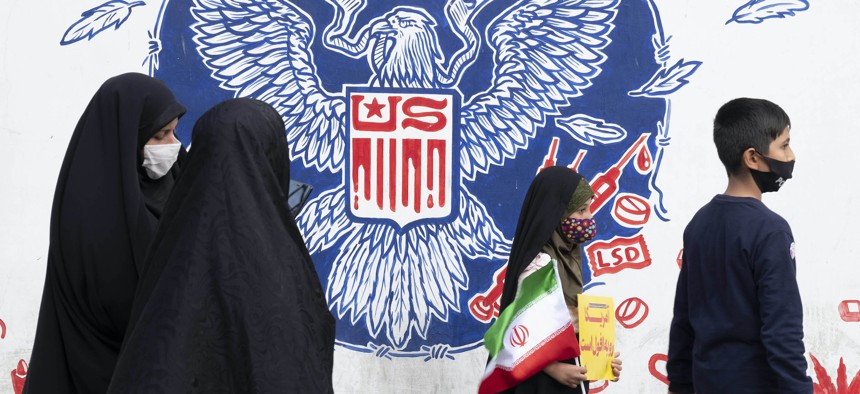 An Iranian schoolgirl carrying an Iran flag walks past an anti-U.S. mural on a wall of the former U.S. embassy after a ceremony to mark the anniversary of the seizure of the U.S. embassy in downtown Tehran, November 4, 2021. 