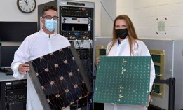 Project Managers James Winter (Air Force Research Laboratory) and Tara Theret (Northrop Grumman) hold models of the photovoltaic and the radio frequency sides of the sandwich tile, while at the Linthicum, Maryland facility, to witness the conversion and beaming experiment.