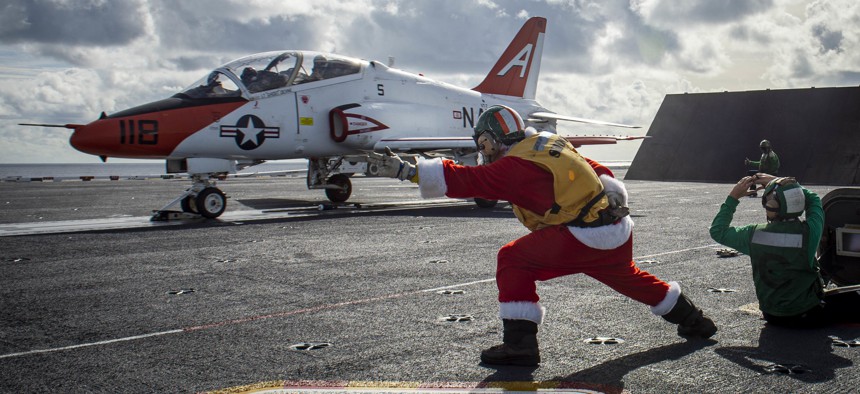 Lt. Cmdr. Rob Nelson, left, a shooter assigned to the aircraft carrier USS George H.W. Bush (CVN 77), launches a T-45C Goshawk aircraft assigned to Training Air Wing (TW) 1, Dec. 18, 2021. 