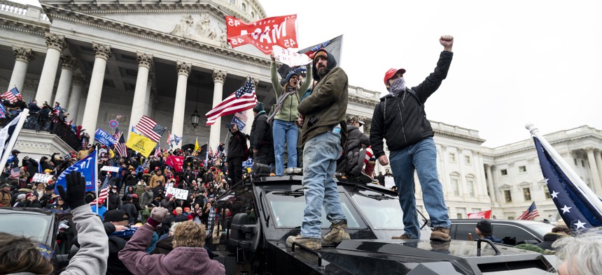 Trump supporters stand on the U.S. Capitol Police armored vehicle as others take over the steps of the Capitol on Wednesday, Jan. 6, 2021, as the Congress works to certify the electoral college votes. 