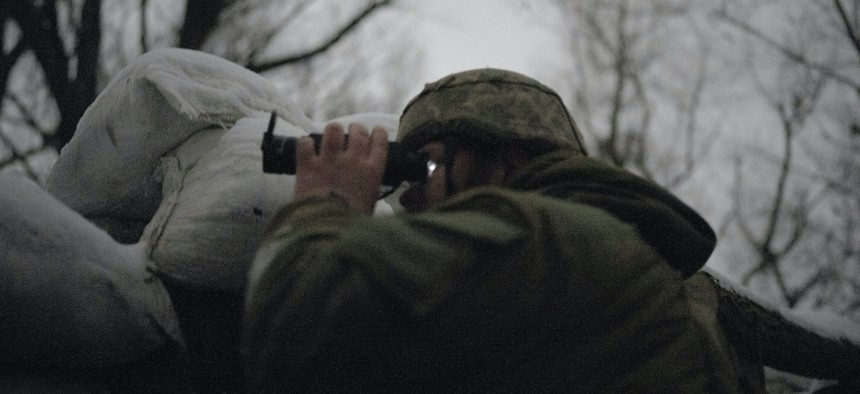 A Ukrainian soldier uses a night vision scope to observe the area from the frontline in Zolote, Ukraine on January 20, 2022.