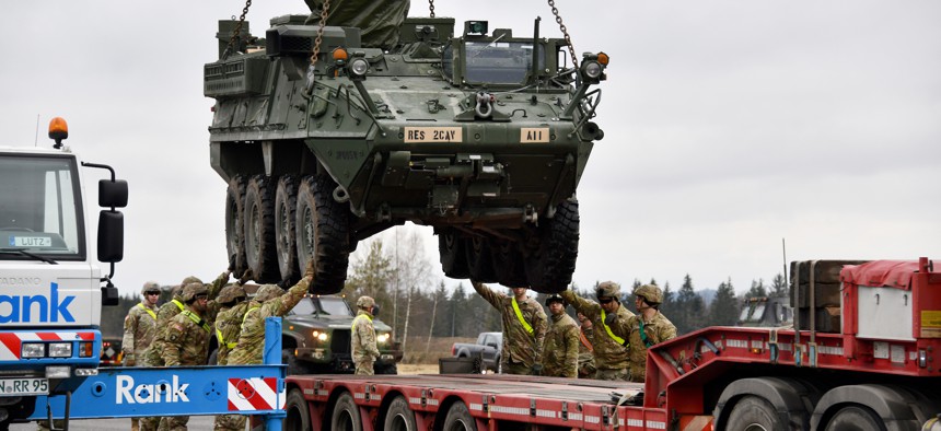 U.S. soldiers with 2nd Squadron, 2nd Cavalry Regiment load a Stryker armored vehicle onto a truck at the 7th Army Training Command’s Rose Barracks Air Field, Vilseck, Germany, Feb. 9, 2022.