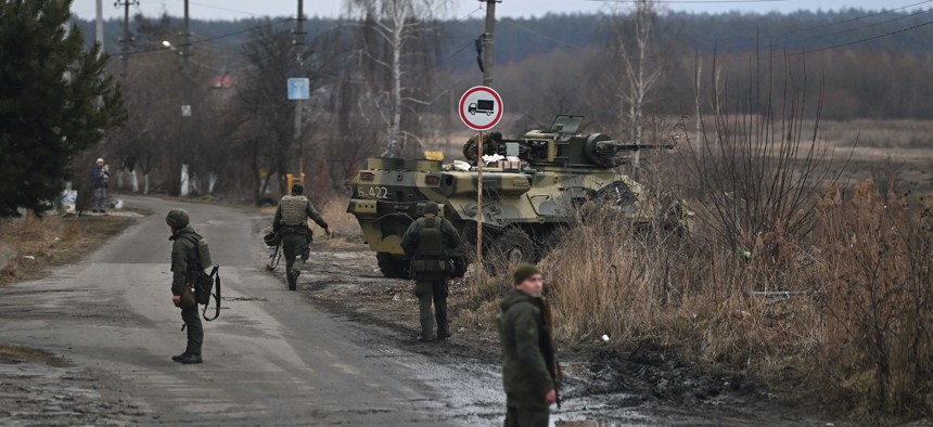 Ukrainian servicemen stand near a BTR-3 armored personnel carrier to the northwest of Kyiv on February 24, 2022.