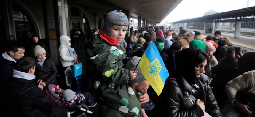 A man holds a child with the Ukrainian flag as they wait for a train on a platform at Kyiv's railway station on March 2, 2022.