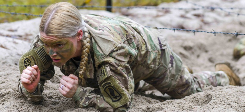 Army Capt. Valerie Nostrant low-crawls under barbed wire during training at Grafenwoehr Training Area, Germany, Dec. 14, 2021.
