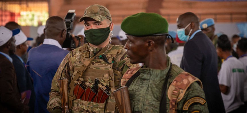 A private security guard from the Russian group Wagner (L) stands next to a Central African Republic soldier during a rally of the United Hearts Movement (MCU) political party at the Omnisport Stadium in Bangui on March 18, 2022.
