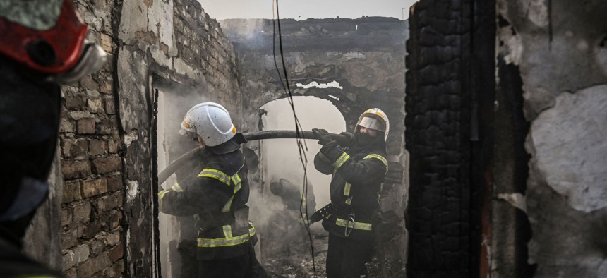 Firefighters extinguish a burning house hit by Russian Grad rockets in Kyiv's Shevchenkivsky district, on March 23, 2022.