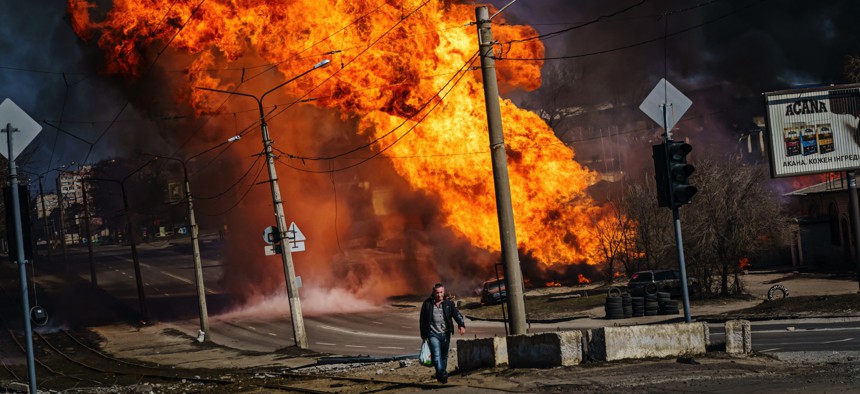 A man walks away from a building set afire by Russian bombardment in Kharkiv, Ukraine, on March 25, 2022.
