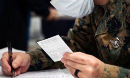 A sailor verifies a COVID-19 vaccine card aboard the Wasp-class amphibious assault ship USS Kearsarge in the Atlantic Ocean, March 23, 2022.