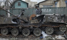 Two people walk past the wreckage of a destroyed Russian tank in Bucha, Ukraine, April 4, 2022.