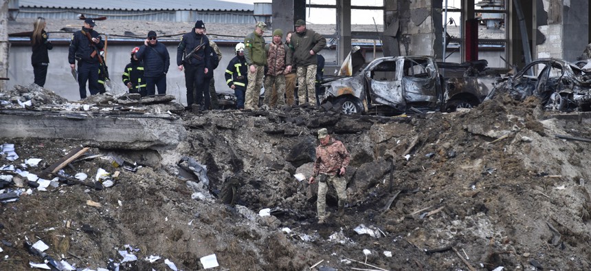 Soldiers inspect the crash site of a Russian missile that hit a car service station in Lviv, Ukraine, on April 18, 2022.