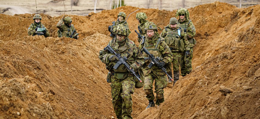 Estonian soldiers advance along a trench as they defend a dug-in position from attacking British armor and infantry as part of NATO exercise Bold Dragon, alongside Danish and French forces, April 14, 2022.