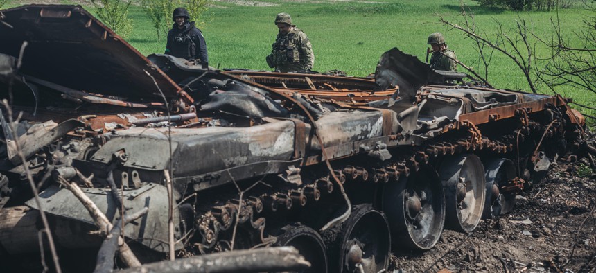 Ukrainian soldiers next to a destroyed Russian tank on the outskirts of Kharkiv, Ukraine, May 8, 2022.