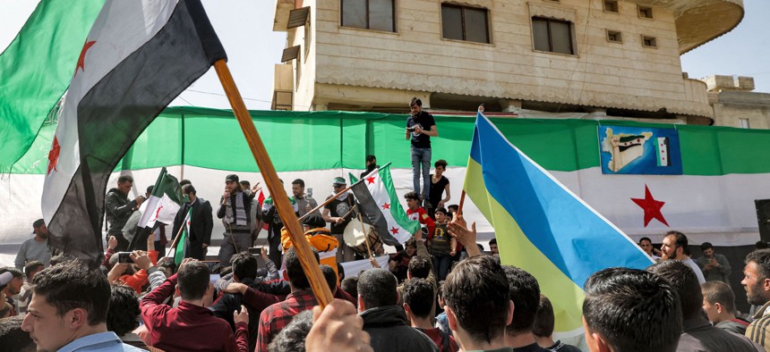 People raise flags of Ukraine and of the Syrian opposition during a demonstration against Russia's invasion of Ukraine in the city of Binnish in Syria's northwestern rebel-held Idlib province on April 1, 2022. 