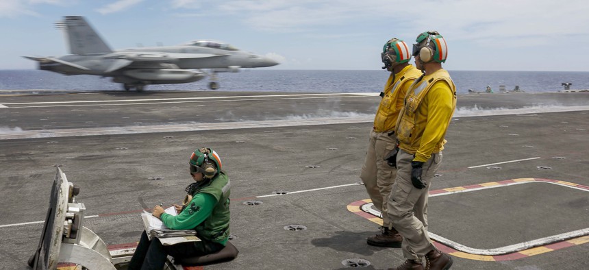 Sailors observe an EA-18G Growler assigned to the "Wizards" of Electronic Attack Squadron (VAQ) 133 launch from the flight deck of the Nimitz-class aircraft carrier USS Abraham Lincoln (CVN 72).