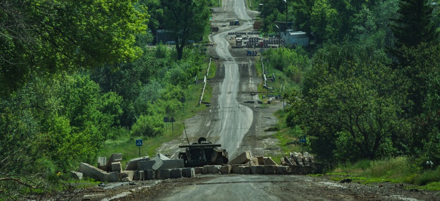 The wreckage of an armored personnel vehicle sits on a road to a Donbas village on June 2, 2022.