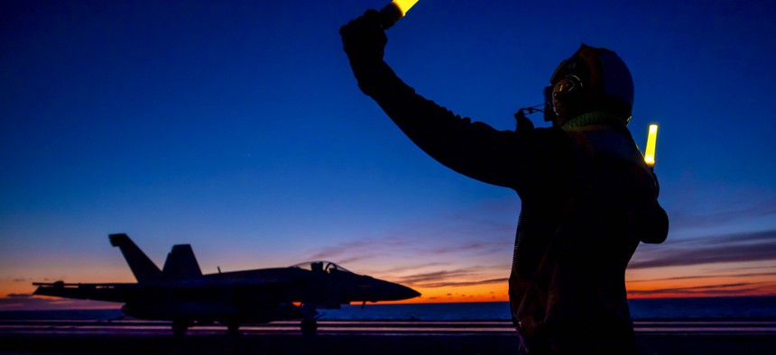 Navy Petty Officer 3rd Class Gzavel Bolton directs an F/A-18E Super Hornet on the flight deck of the USS Harry S. Truman in the Mediterranean Sea, Jan. 29, 2022.
