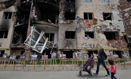 A woman and her daughter walk past a residential building destroyed as a result of shelling in town of Irpin, near the Ukrainian capital of Kyiv on June 16, 2022.