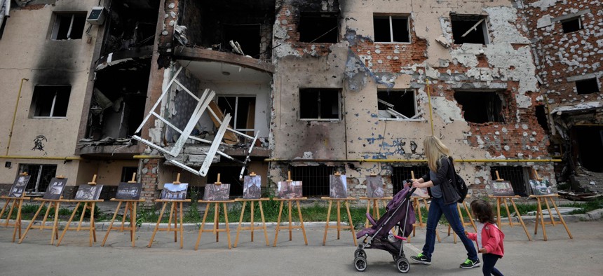 A woman and her daughter walk past a residential building destroyed as a result of shelling in town of Irpin, near the Ukrainian capital of Kyiv on June 16, 2022.