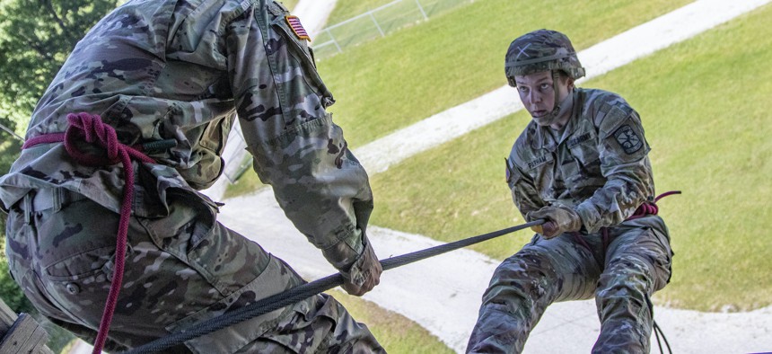 Sgt. Richard Morales, left, a rappel master from the 10th Mountain Division, guides a cadet down the rappel tower on Fort Knox, Ky, June 20. 