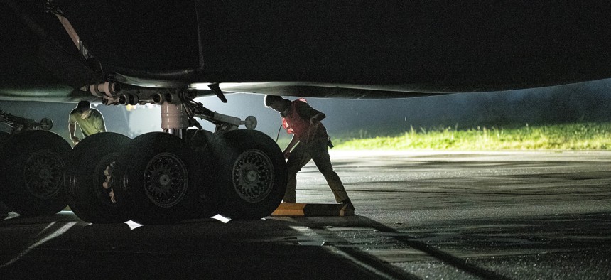 A service member, assigned to 34th Aircraft Maintenance Unit, places chocks on a B-1B Lancer, assigned to 34th Expeditionary Bomb Squadron, at Andersen Air Force Base, Guam, after returning from a Bomber Task Force mission with the Royal Australian Air Force, June 22, 2022. 