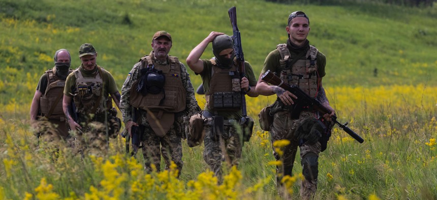 Azov Regiment soldiers walk through a field for tactical training on June 28, 2022, in Ukraine's Kharkiv region.
