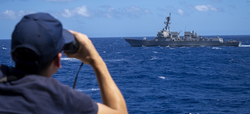 U.S. Coast Guard crew member aboard cutter USCGC Midgett (WMSL 757) looks out at Arleigh Burke-class guided-missile destroyer USS Gridley (DDG 101) during a ship maneuvering exercise as part of Rim of the Pacific (RIMPAC) 2022.