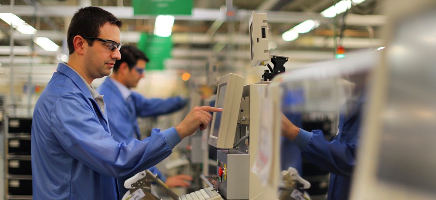 Workers monitor circuit card assembly machines at a Raytheon facility in Massachusetts. 