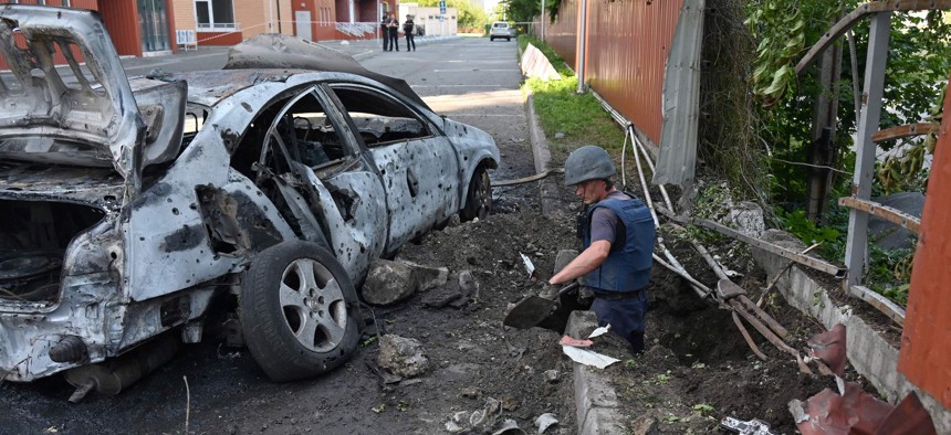 Deminers examine the site of a reported cluster munition fall after a rocket attack on a residential area in northern Kharkiv, Ukraine, on August 8, 2022.