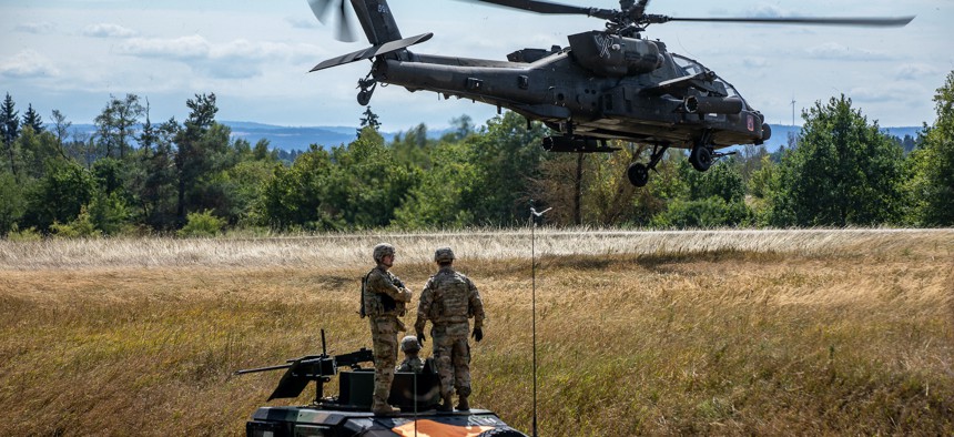 Soldiers assigned to the 1st Battalion, 3rd Aviation Regiment (Attack Reconnaissance), 12th Combat Aviation Brigade, look on as an AH-64D Apache Longbow Helicopter flies overhead during the Viper Battalion family day event at Grafenwoehr Training Area, Germany, August 6, 2022. 