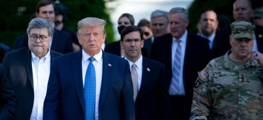 Then-President Donald Trump walks with Attorney General William Barr (L), Defense Secretary Mark Esper (C), Chairman of the Joint Chiefs of Staff Mark Milley (R), and others from the White House to visit St. John's Church after the area was cleared of people protesting the death of George Floyd, on June 1, 2020.