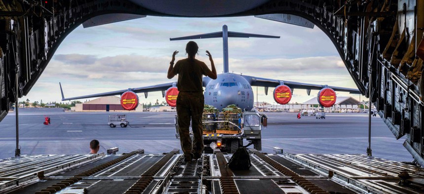 Senior Airman Jolan Besse, 535th Airlift Squadron loadmaster, directs a k-loader to load cargo onto a C-17 Globemaster III in support of an airdrop exercise at Joint Base Pearl Harbor-Hickam, Hawaii, Aug. 24, 2022.