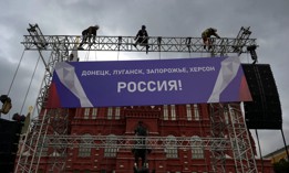 Workers fix a banner reading "Donetsk, Lugansk, Zaporizhzhia, Kherson - Russia!" on top of a construction installed in front of the State Historical Museum outside Red Square in central Moscow on September 29, 2022.