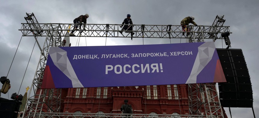 Workers fix a banner reading "Donetsk, Lugansk, Zaporizhzhia, Kherson - Russia!" on top of a construction installed in front of the State Historical Museum outside Red Square in central Moscow on September 29, 2022.