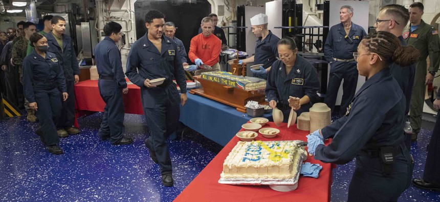 Sailors serve cake during the Navy birthday celebration on the mess decks of amphibious assault carrier USS Tripoli (LHA 7) Oct. 13, 2022.