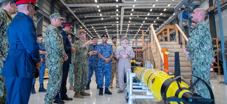 Vice Adm. Brad Cooper, commander of U.S. Naval Forces Central Command (NAVCENT), U.S. 5th Fleet and Combined Maritime Forces, center right, along with Major Gen. Ala Abdulla Seyadi, commander of the Bahrain Coast Guard, center left; and Rear Adm. Mohammed Yousif Al Asam, commander of the Royal Bahrain Naval Force, right, listen to a presentation on a Razorback unmanned underwater vehicle.