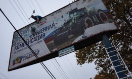 A local resident in recently liberated Kherson, Ukraine, tears apart a billboard emblazoned "We together with Russia" on November 13, 2022. 