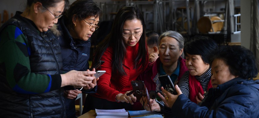 A 2021 photo shows people learning to use smartphones at a senior citizens' university in Taiyuan in China's Shanxi Province. 