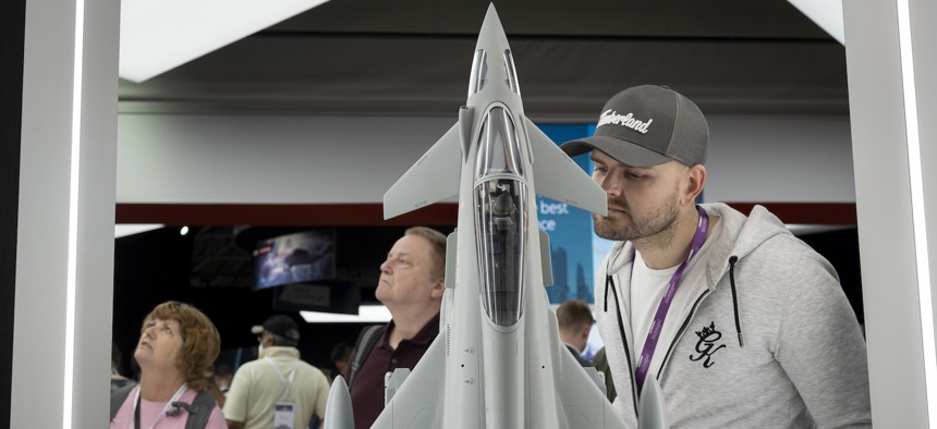 Visitors to the BAE exhibition stand look at a scaled model of a Typhoon fighter jet during the Farnborough Airshow, on July 22, 2022, in England. 