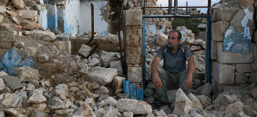 A man sits in the ruins of the northern Syrian town of Ahsem in October 2022.