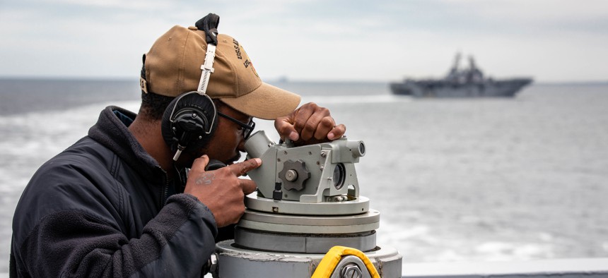 A sailor takes a bearing aboard the San Antonio-class amphibious transport dock ship USS Arlington (LPD 24) during a multinational exercise in the Baltic Sea on Aug. 3, 2022.