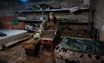 "Kava," a Ukrainian frontline paramedic, uses a Starlink internet connection in a basement in eastern Ukraine's Donbas region as Russian shells explode nearby on February 20, 2023.