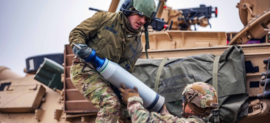 Army Staff Sgts. Ross Wilcoxson, left, and Marcus Kearse, both M1 armor crewmen assigned to Apache Company, 1st Battalion, 9th Cavalry Regiment, 2nd Armored Brigade Combat Team, 1st Cavalry Division, load ammunition onto a M1A2 Abrams tank during a live-fire exercise at Bemowo Piskie, Poland, Feb. 16, 2023.