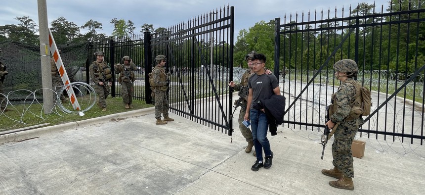 A roleplayer is escorted through an entry control point as the 26th Marine Expeditionary Unit practices non-combatant evacuation on April 24, 2023, at Camp Lejeune, North Carolina.
