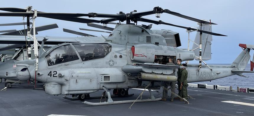 Marines from the 26th Marine Expeditionary Force work on an AH-1Z Viper attack helicopter on the flight deck of the USS Bataan on April 24, 2023. 