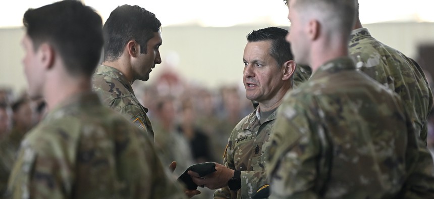 Then-Command Sergeant Major Michael Weimer presents a green beret to a graduate during a Regimental First Formation at Fort Bragg, North Carolina August 18, 2022.